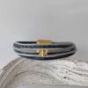 Lederarmband mit einer goldener Biene in blau-grau
