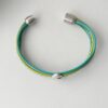 das Lederarmband mit einer Muschel in grün und türkis
