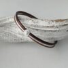 das Lederarmband in braun mit einem weißem Stein